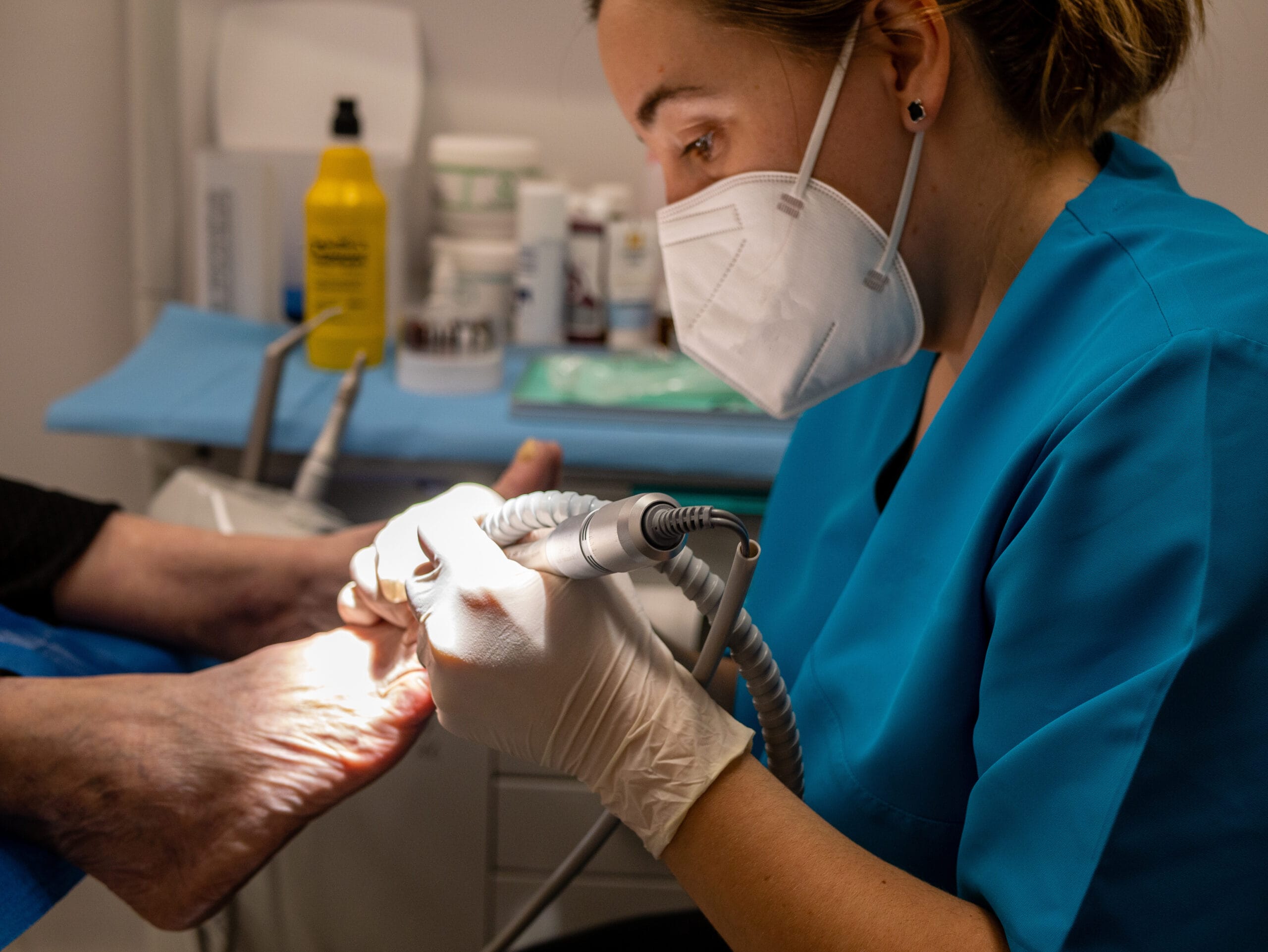 femme podiatre portant masque medical gants traitant pieds client scaled